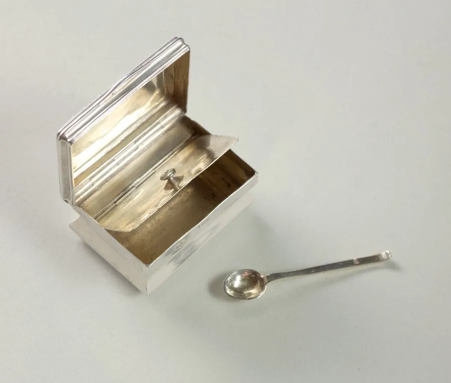 A silver snuff box with its spoon.