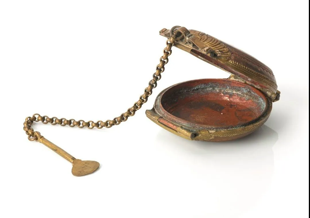 A copper pocket snuff box with a shovel-shaped spoon on a chain.
